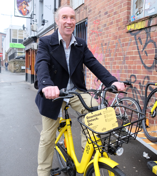 Cllr Douglas Johnson riding an Ofo bike