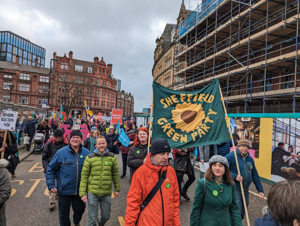 Green Party members marching with the banner