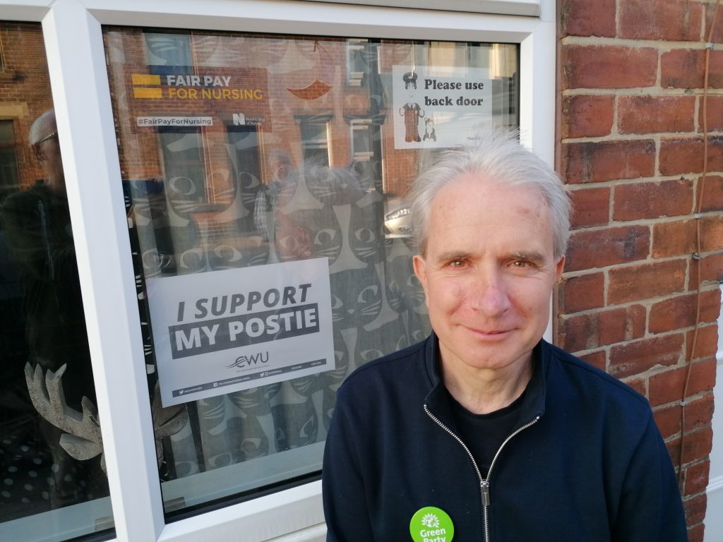 Toby Mallinson with window poster saying "I support my postie."