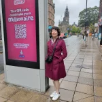 Cllr Ruth Mersereau next to a giant digital advertising board near Sheffield Town Hall